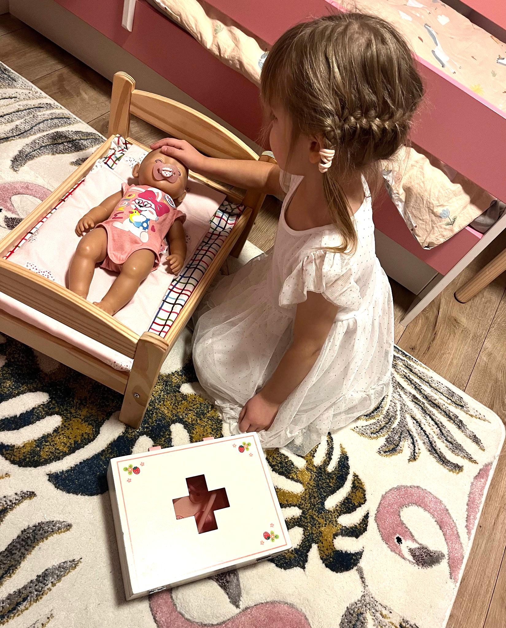 Tüdruk mängib puidust arsti komplektiga